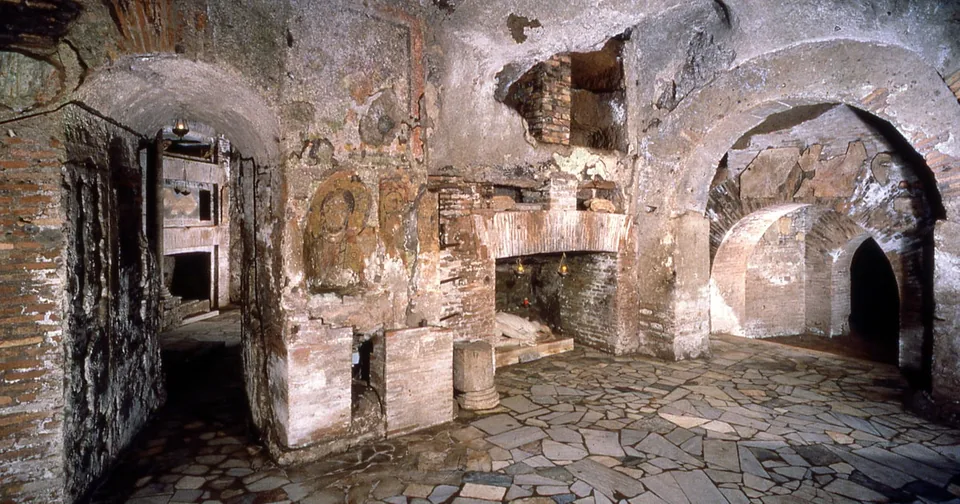 An underground corridor carved into tuff, with niches and warm lighting